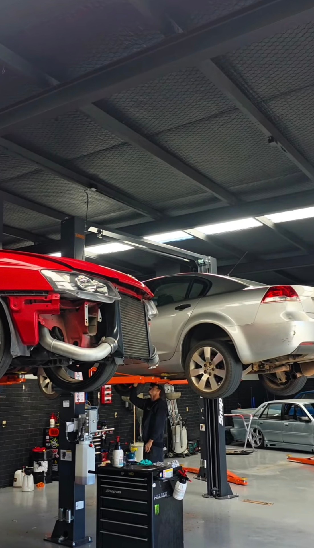 Two vehicles on hoists inside the All In workshop